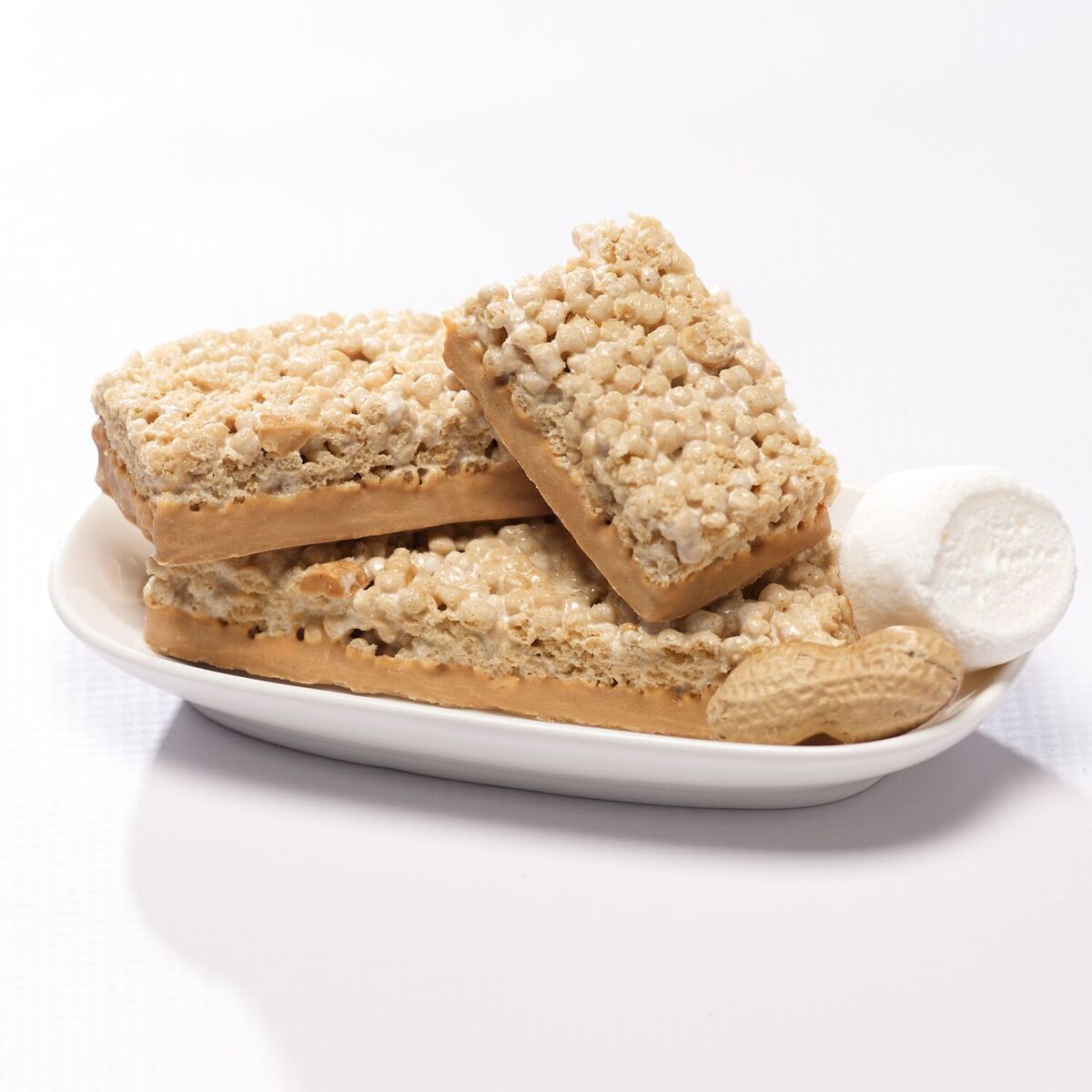 Fluffy Peanut Butter Protein bars on white dish with peanuts and marshmallow