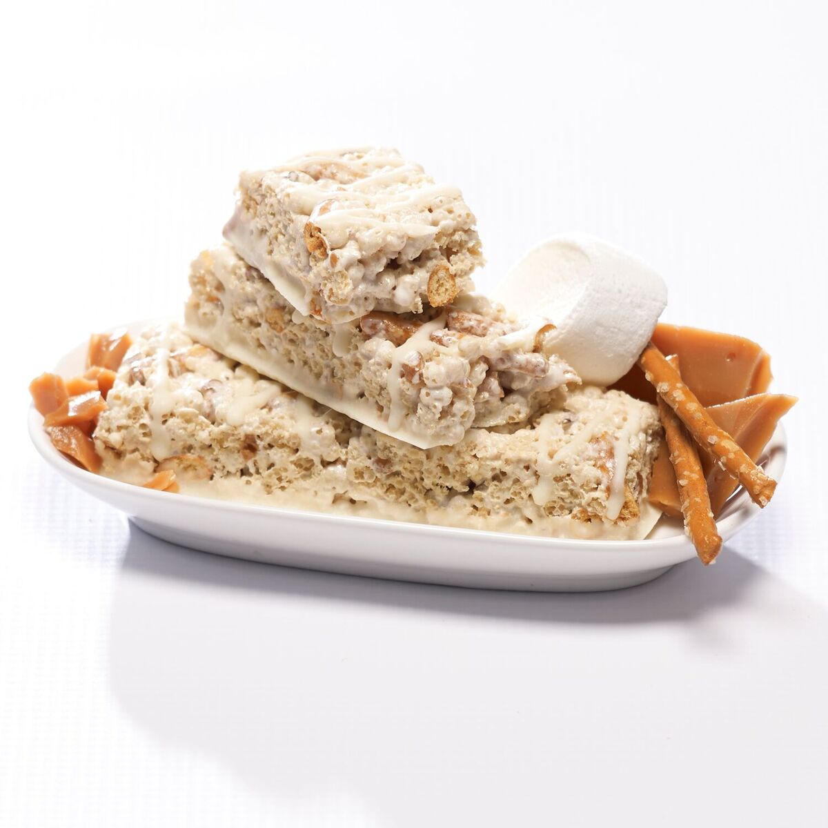 Salted toffee pretzel protein bars  with toffee and pretzels on white dish